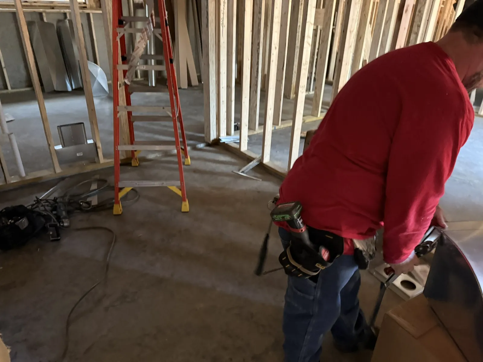 Technician assembling sheet metal ductwork on the floor of an open-framed new build