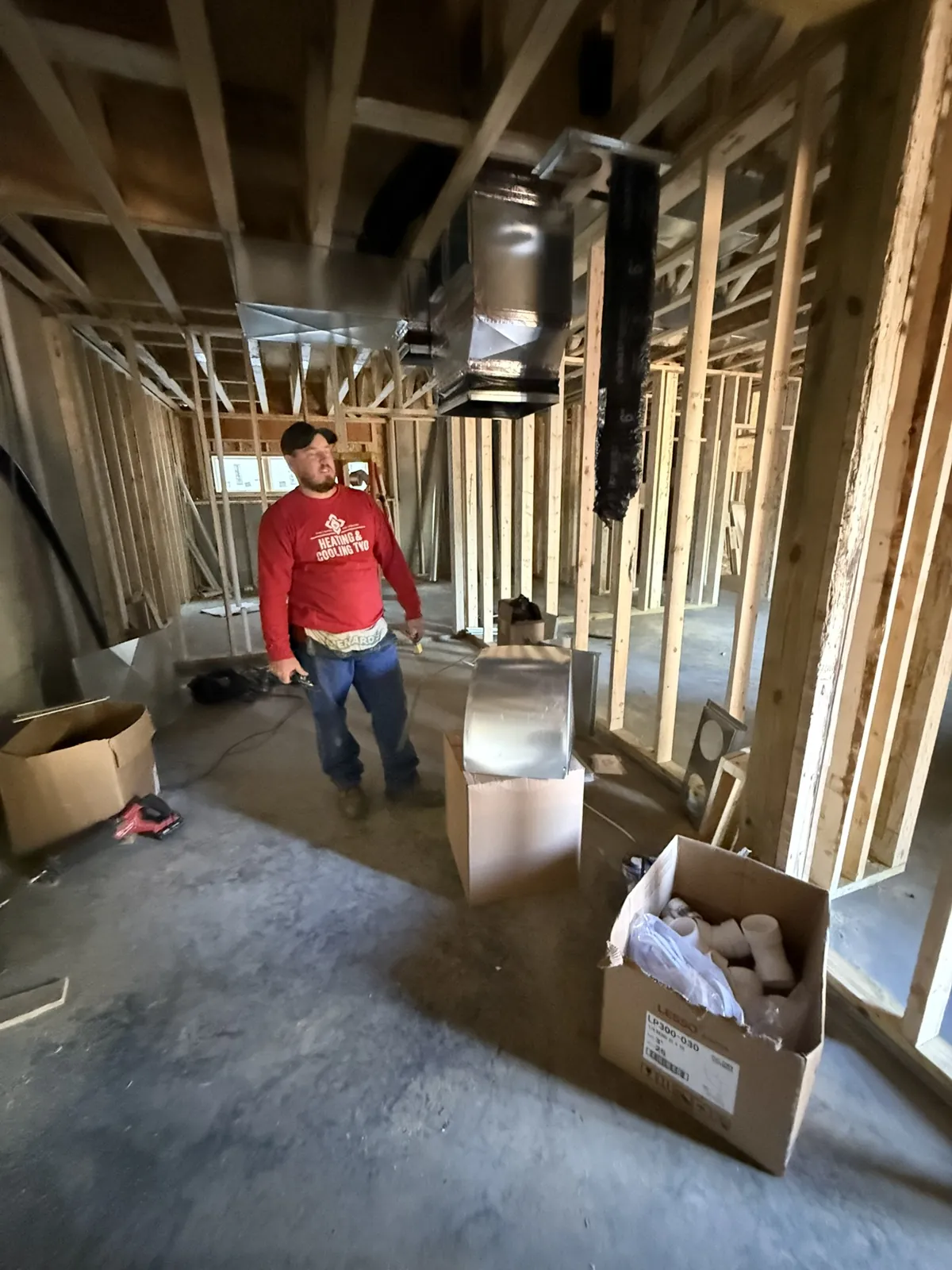 Supply trunk line hung overhead with fittings staged on site at a new construction project