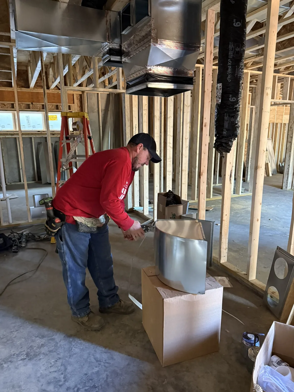 Technician fitting a duct section on site with new trunk lines hung overhead