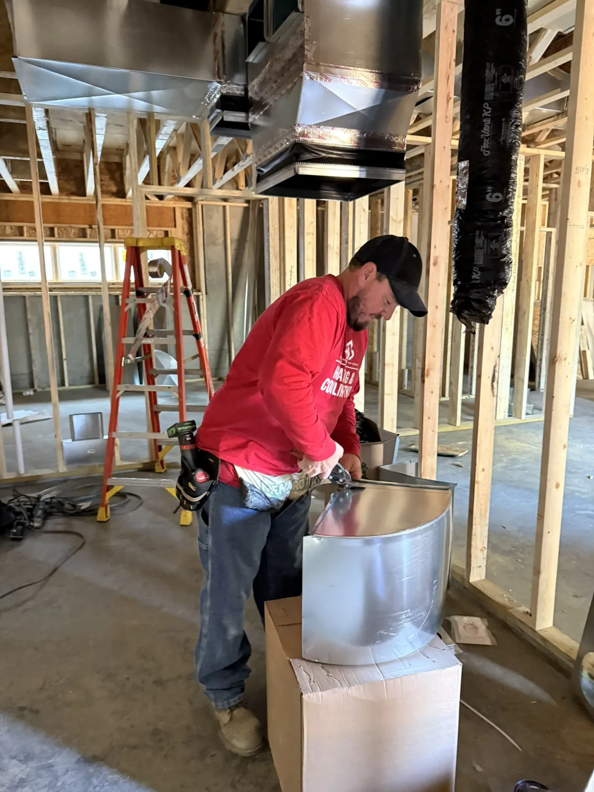 Heating & Cooling Two technician fitting a round duct section on a new construction job