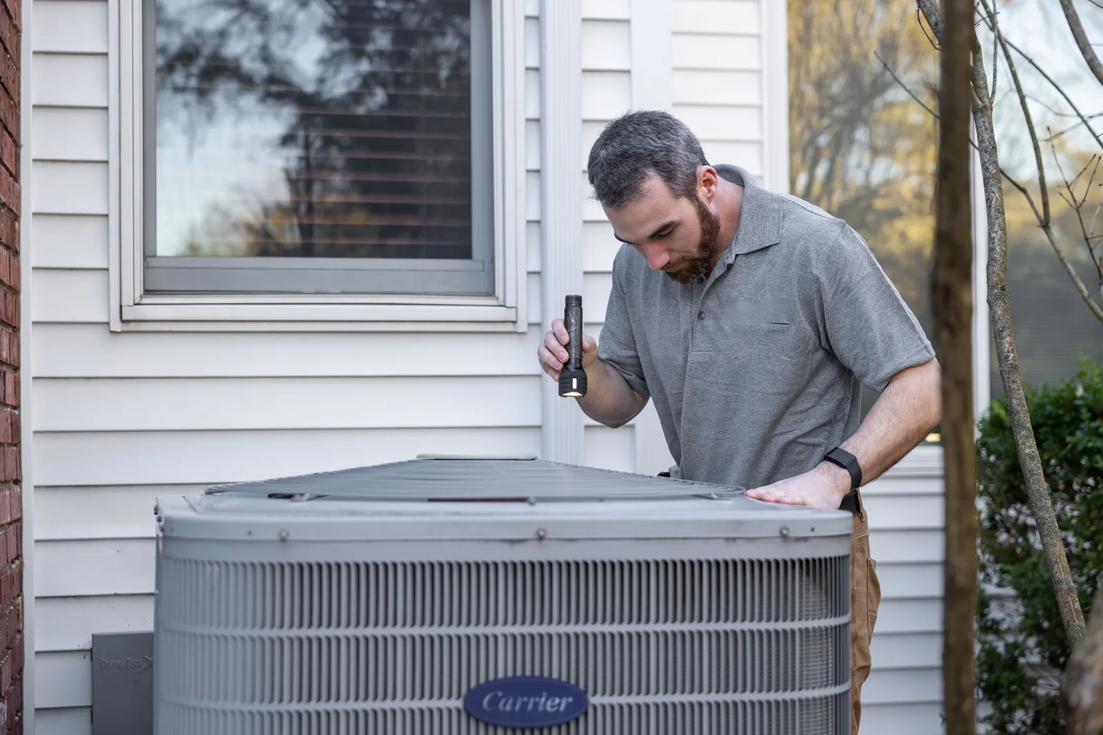 Technician servicing a residential AC condenser